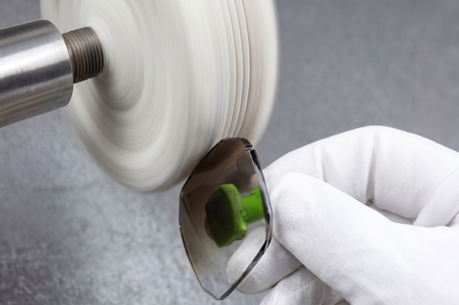 A gloved hand carefully polishing the edge of a lens